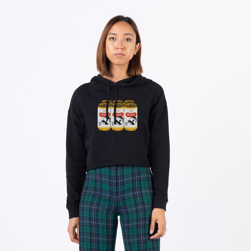 front of woman standing wearing black cropped hoodie with 6 pack of national bohemian beer on it