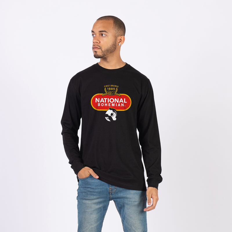 front of man wearing black long sleeve with first brewed 1885" crest and national bohemian logo on it