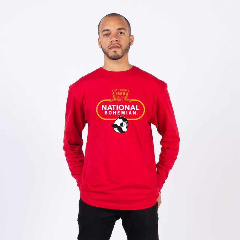 front of man wearing red long sleeve with first brewed 1885" crest and national bohemian logo on it
